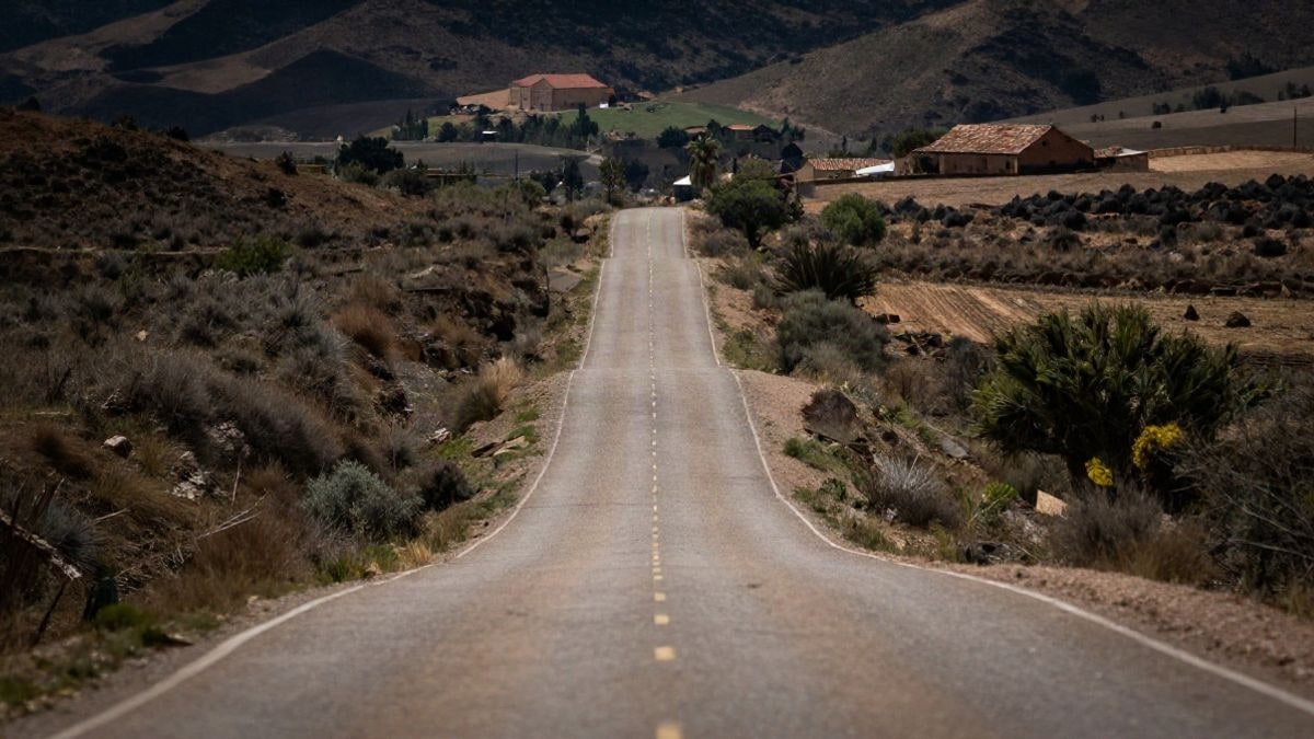 Imagen ilustrativa: camino rural que atraviesa un paisaje minero con líneas que convergen hacia las colinas