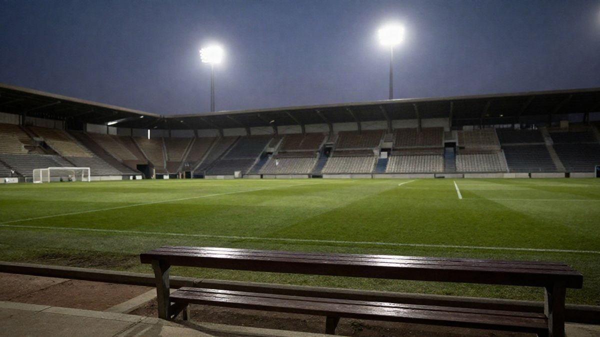Imagen ilustrativa: túnel de vestuarios de un estadio de fútbol iluminado al atardecer, con un banquillo vacío en primer plano.