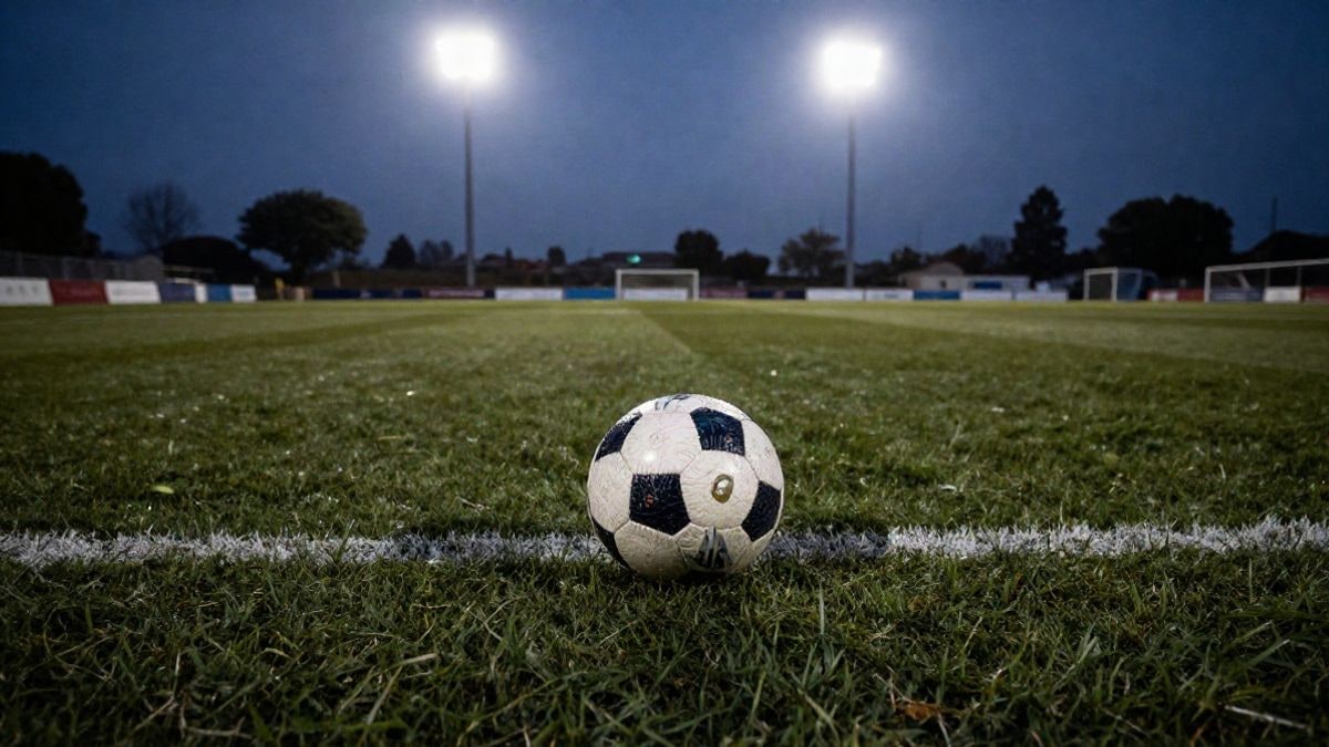 Imagen ilustrativa: balón de fútbol sobre el césped mojado al atardecer, con los focos del estadio encendidos de fondo