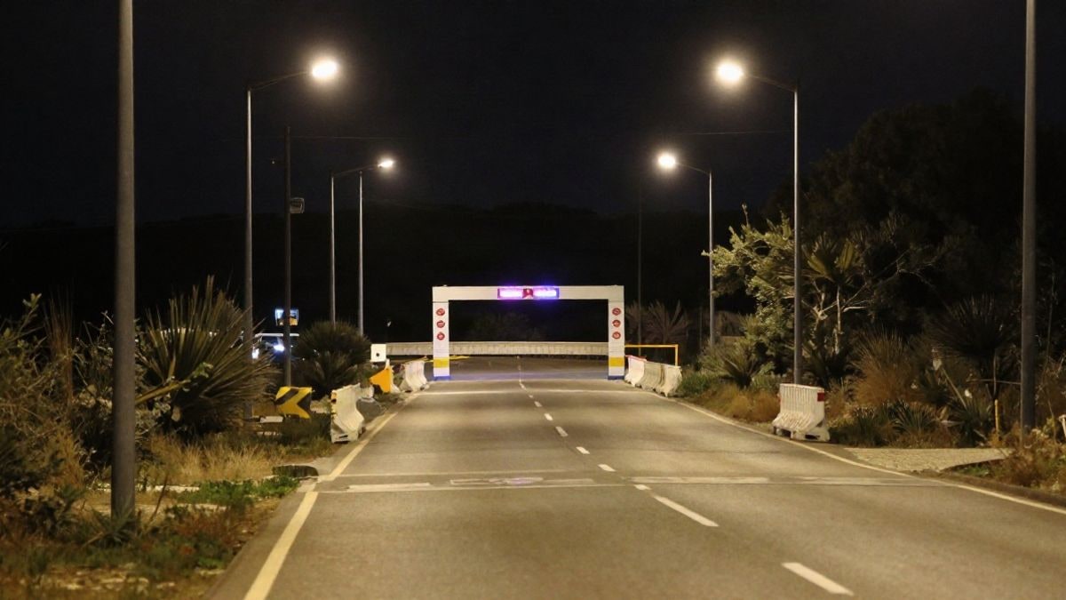 Imagen ilustrativa: carretera vacía iluminada por farolas y un arco de meta de fondo, sin personas ni textos.