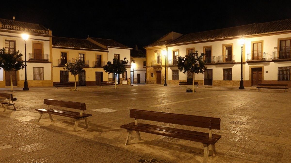 Imagen ilustrativa: plaza de un pueblo español de noche con farolas encendidas y calles vacías