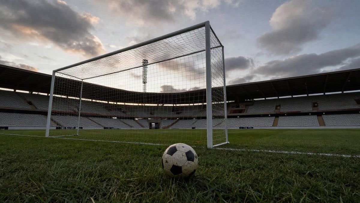 Imagen ilustrativa: estadio de fútbol vacío al amanecer, con un balón en el punto de penalti y los postes de la portería recortados contra el cielo.