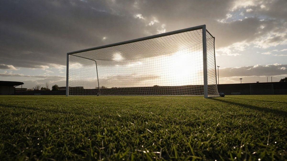 Imagen ilustrativa: ángulo bajo de una portería de fútbol con la red recortada contra el cielo al atardecer