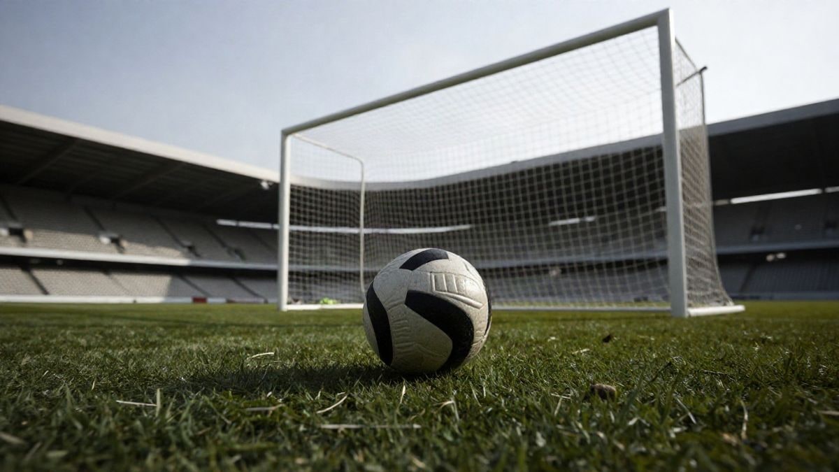 Imagen ilustrativa: un balón de fútbol sobre el punto de penalti en un estadio vacío, con la portería al fondo.