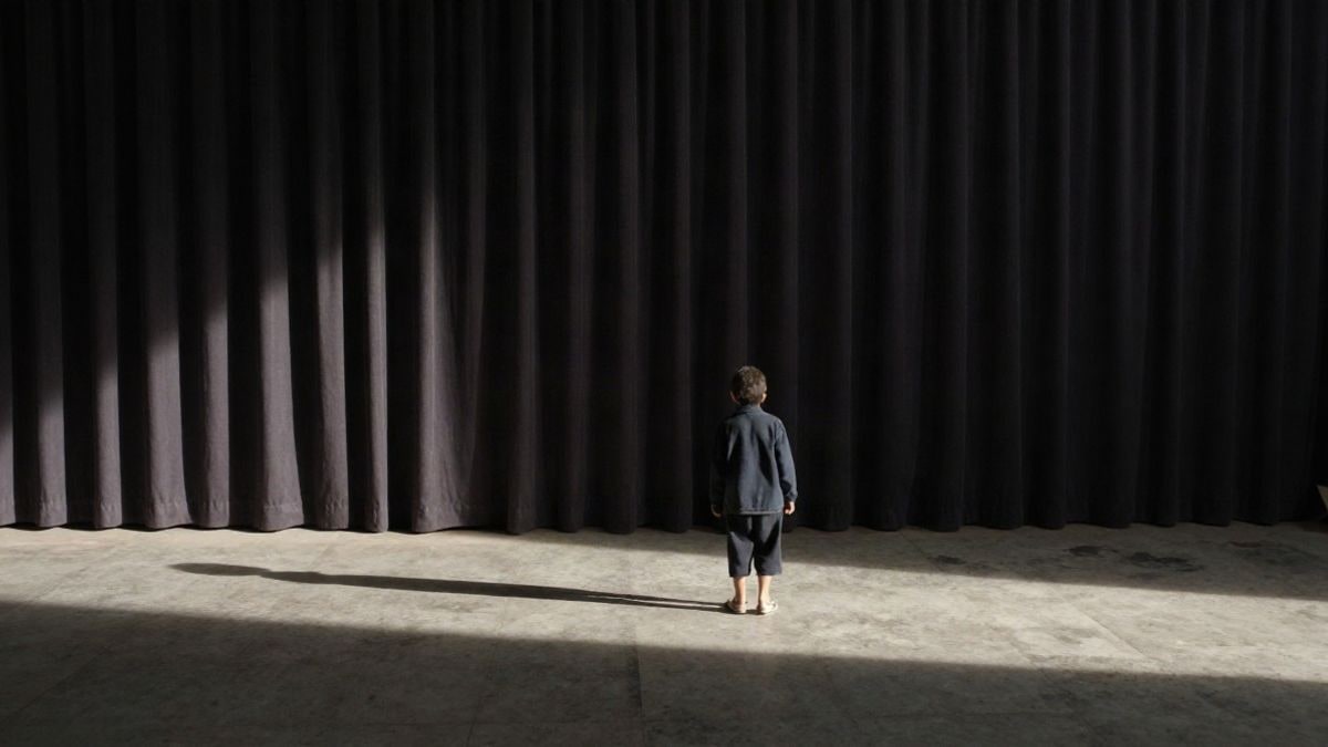 Imagen ilustrativa: un escenario vacío con una figura lejana y un foco de luz