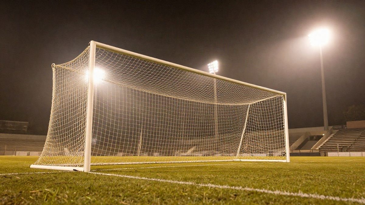 Imagen ilustrativa: focos de un estadio de fútbol iluminados de noche sobre una portería vacía