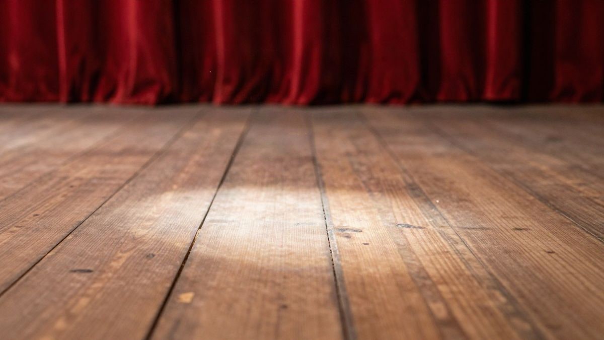 Imagen ilustrativa: detalle del suelo de madera de un escenario teatral iluminado por un foco