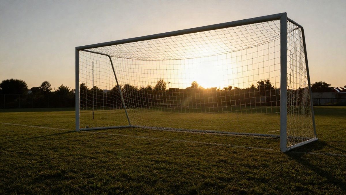 Imagen ilustrativa: portería de fútbol con red a contraluz al atardecer sobre el césped