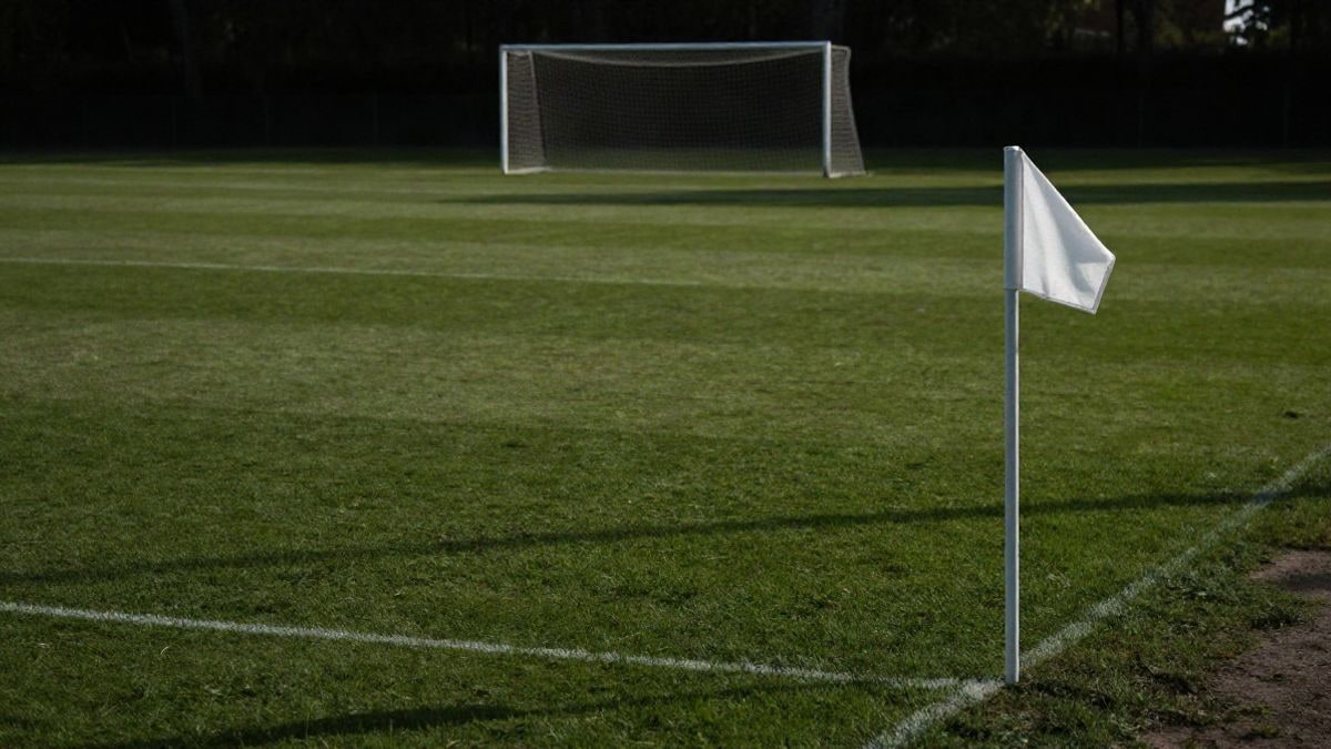 Imagen ilustrativa: un campo de fútbol vacío al atardecer, con un banderín de córner pequeño descentrado y mucho espacio de hierba