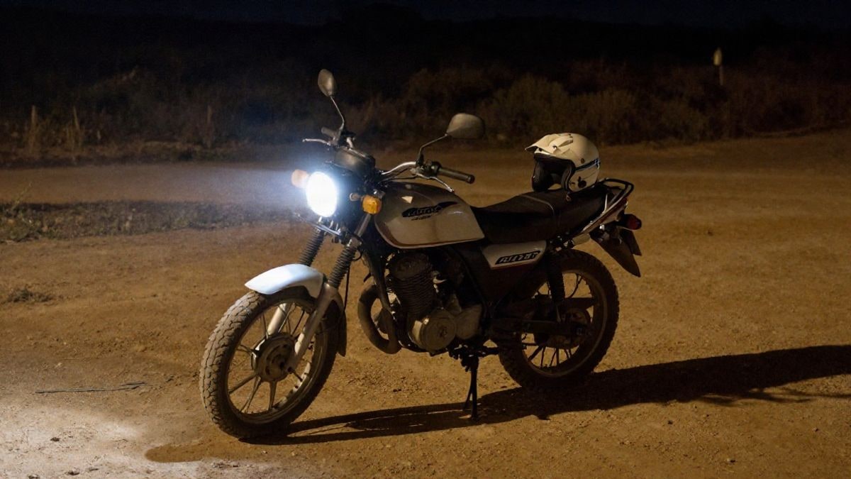 Imagen ilustrativa: moto de rally raid aparcada en un camino de tierra bajo un foco nocturno