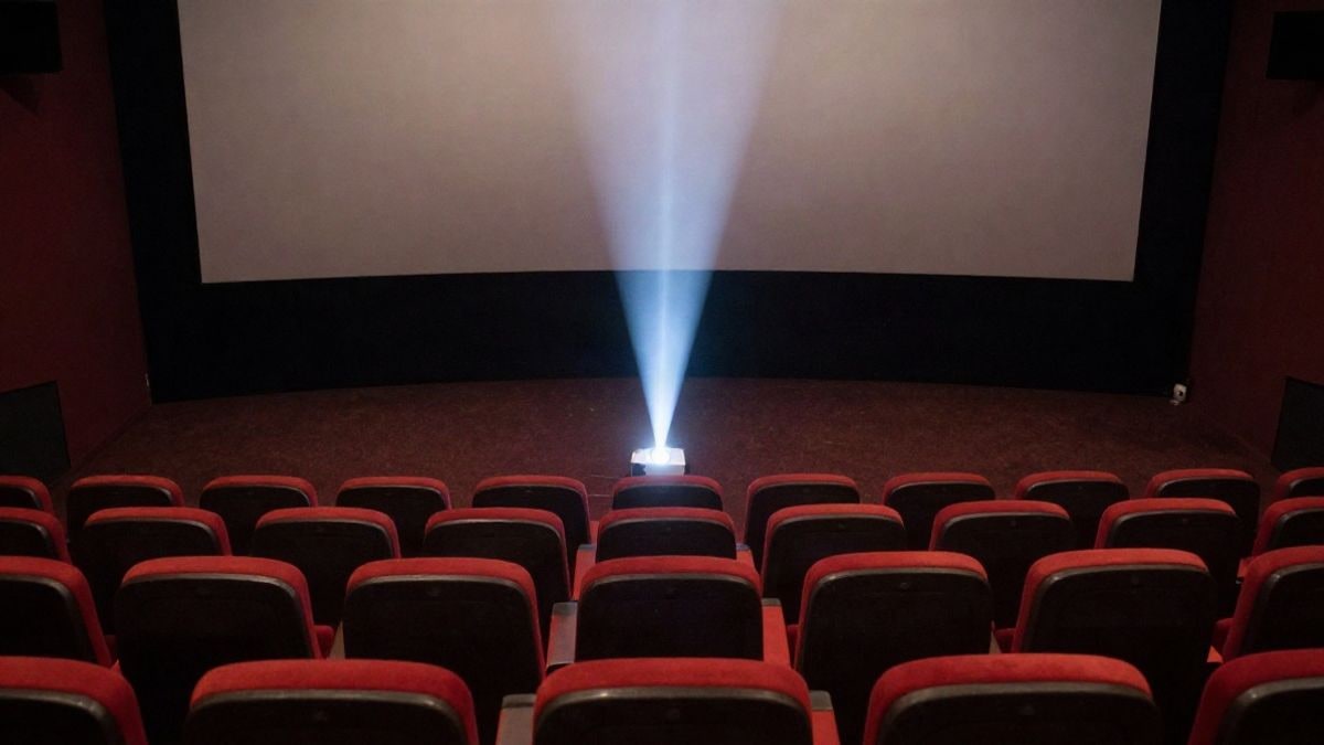 Imagen ilustrativa: vista cenital de una sala de cine vacía con haces de luz sobre la pantalla