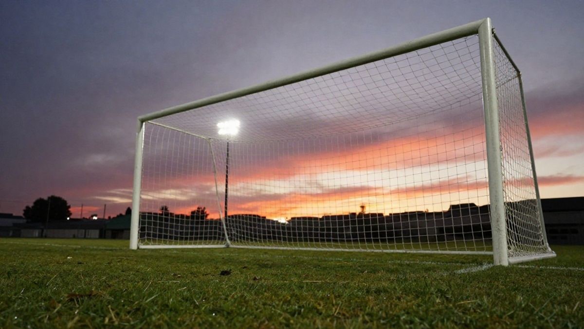Imagen ilustrativa: ángulo bajo de una portería de fútbol con la red y el punto de penalti bajo un cielo al atardecer