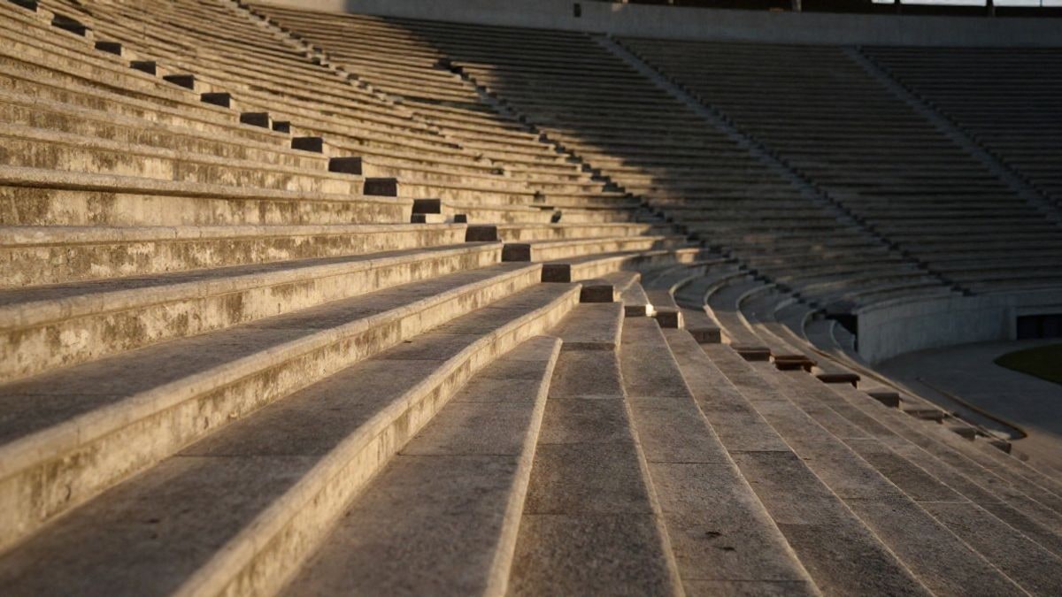 Imagen ilustrativa: gradas de hormigón de un estadio de fútbol vistas en gran angular al atardecer.
