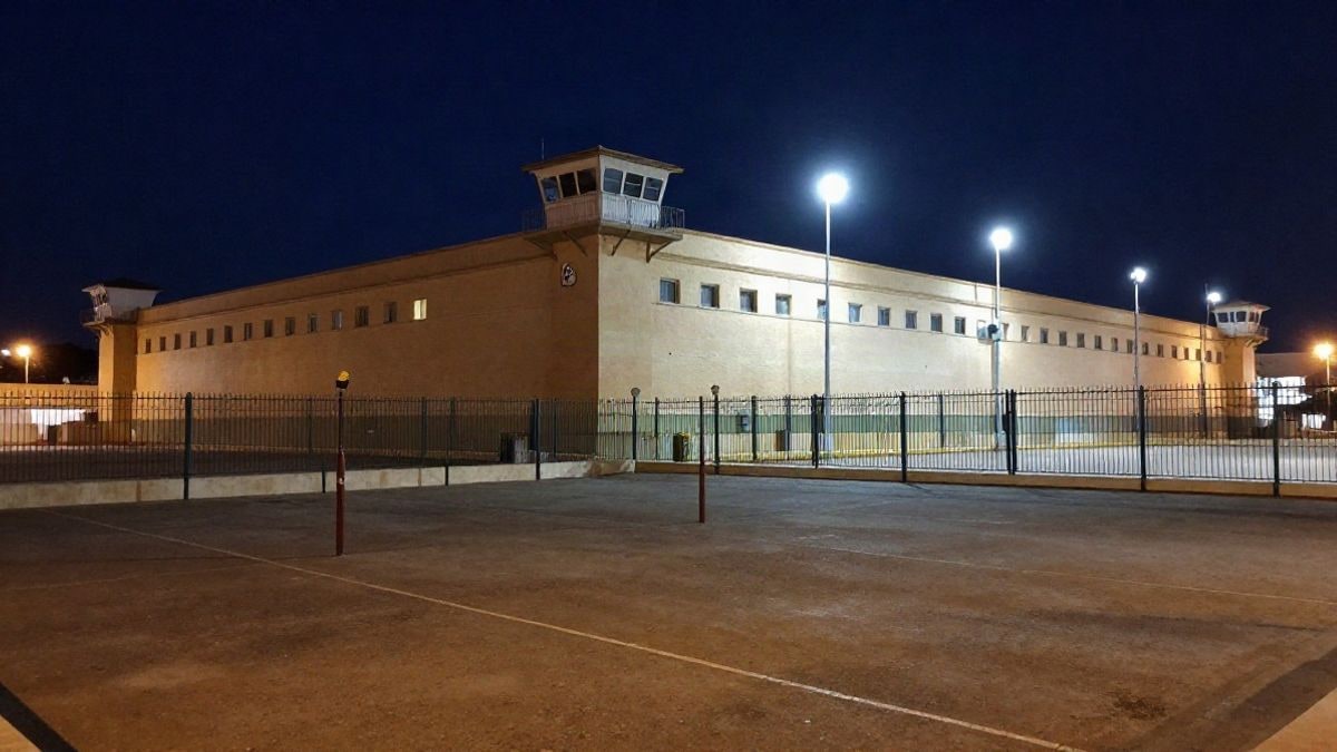 Imagen ilustrativa: vista nocturna de un centro penitenciario genérico con muros perimetrales y focos de luz artificial