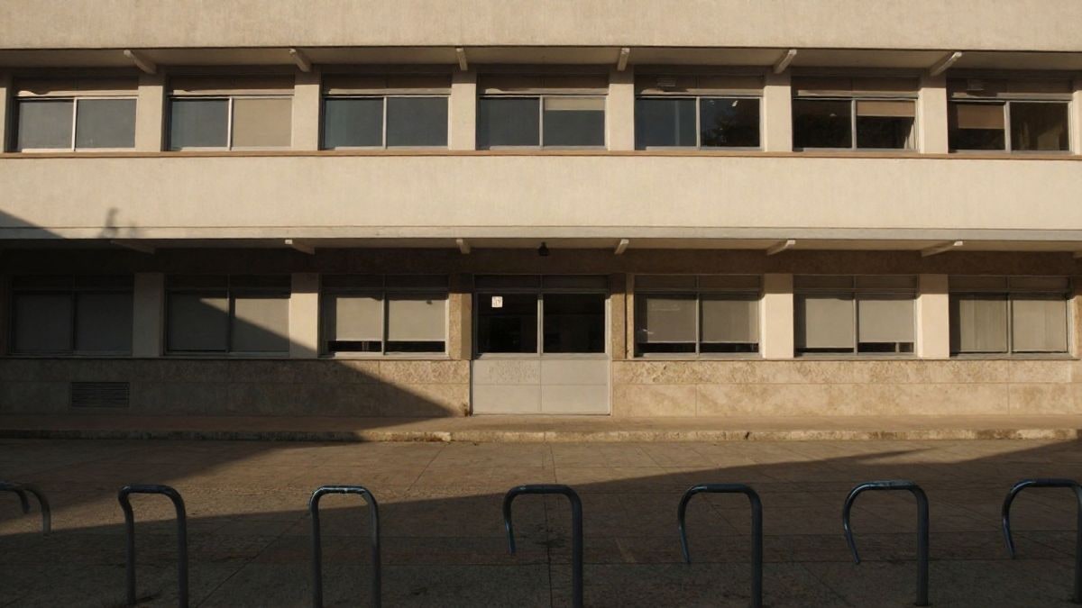 Imagen ilustrativa: fachada genérica de un instituto con ventanas cerradas y bicicletas aparcadas al atardecer