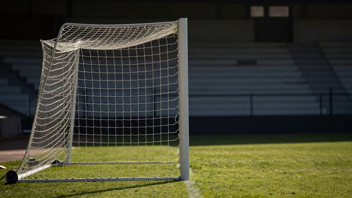 Imagen ilustrativa: red de portería de fútbol con luz natural y césped en primer plano