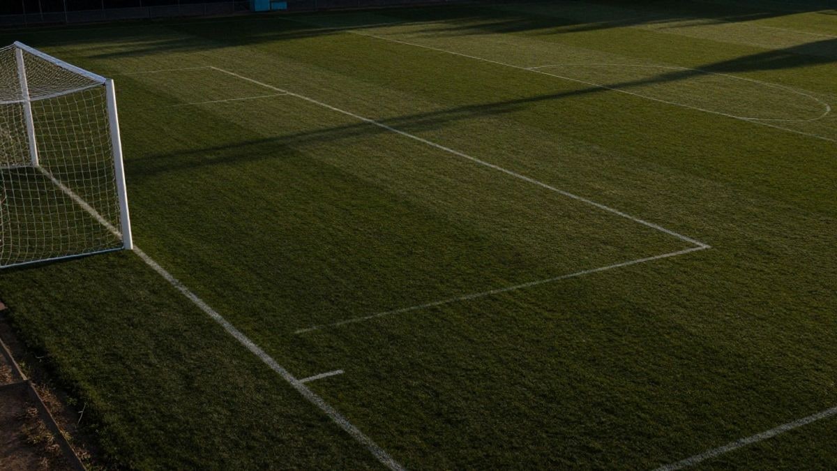 Imagen ilustrativa: vista cenital de un campo de fútbol al atardecer con la portería y el punto de penalti