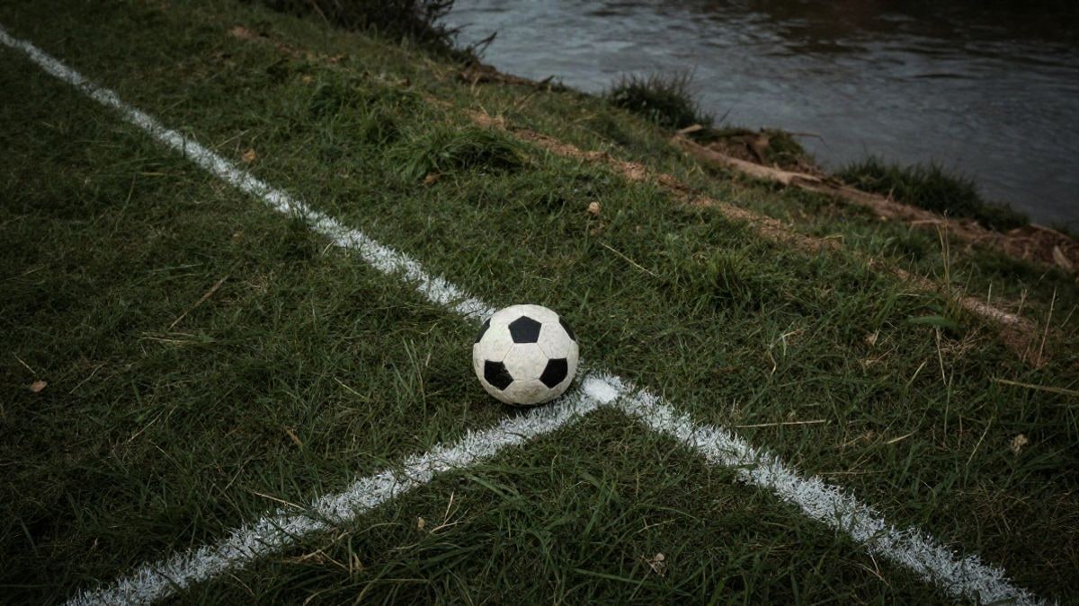 Imagen ilustrativa: vista cenital de un campo deportivo junto a un río con un balón en el césped