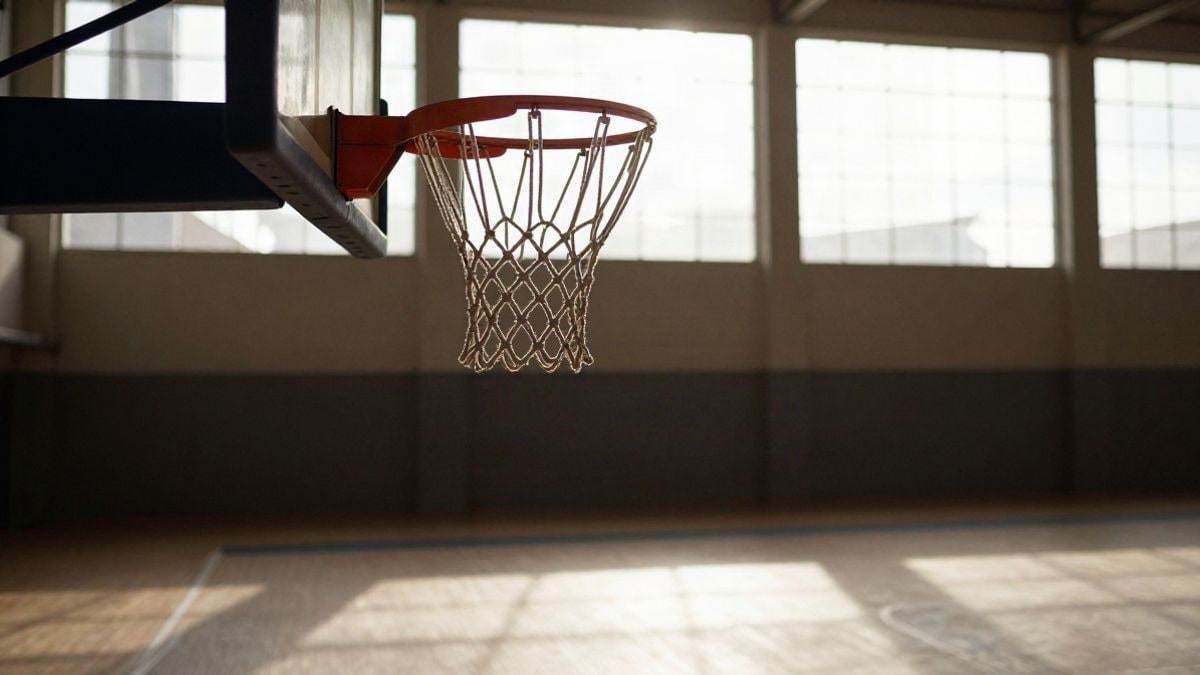 Imagen ilustrativa: canasta de baloncesto con red enfocada y pabellón vacío al fondo