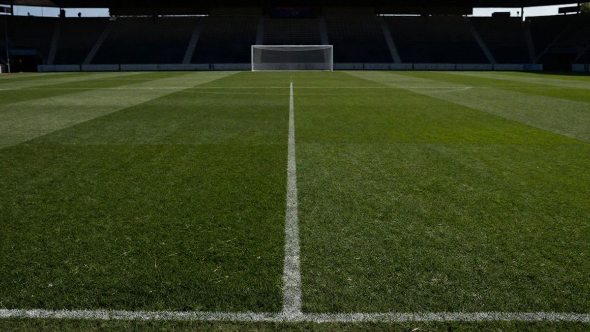 Imagen ilustrativa: campo de fútbol con líneas que convergen hacia una portería al atardecer