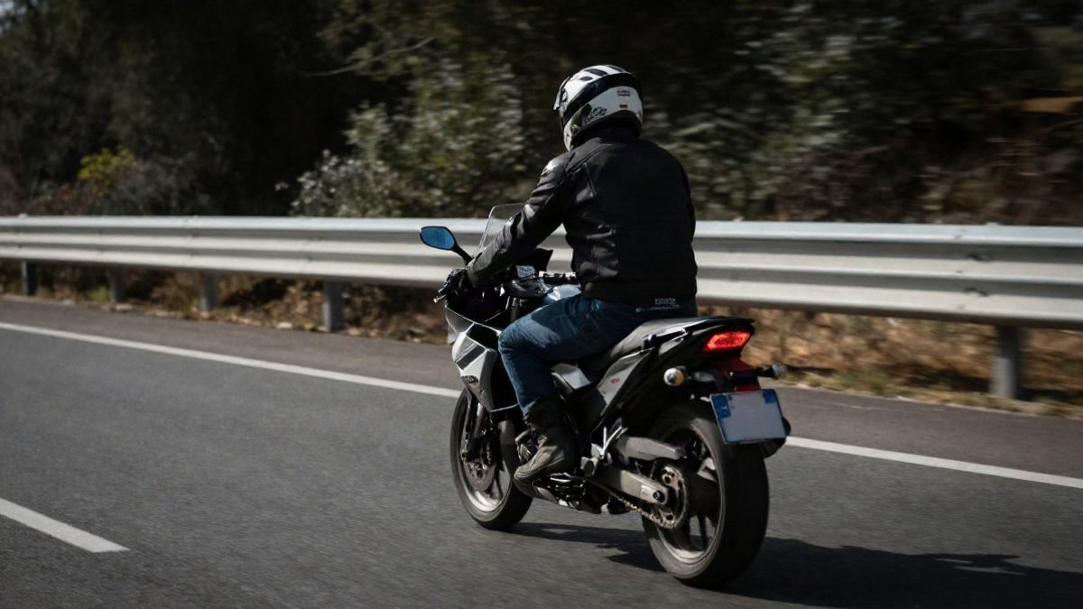 Imagen ilustrativa: un motorista circulando a gran velocidad por una carretera, visto desde atrás, con movimiento borroso.