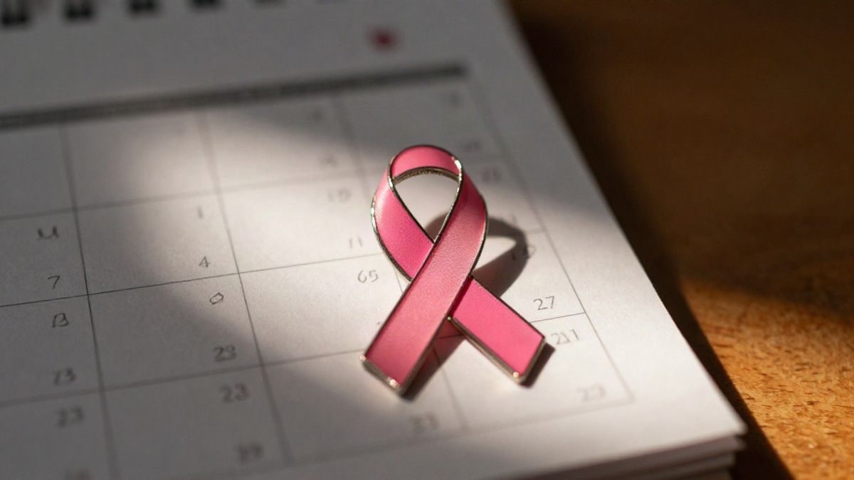 Imagen ilustrativa: lazo rosa sobre un calendario de papel doblado, con luz cálida de atardecer