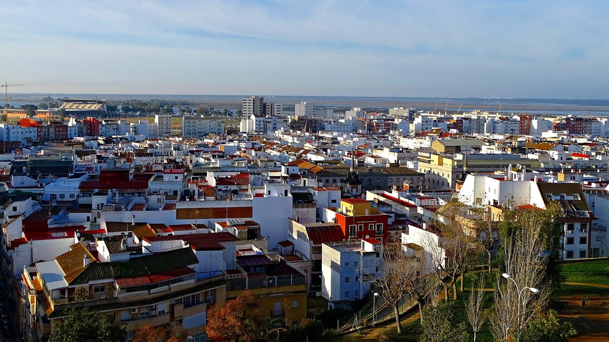 Vista aérea del casco urbano de Huelva, con casas blancas y tejados rojos bajo el cielo