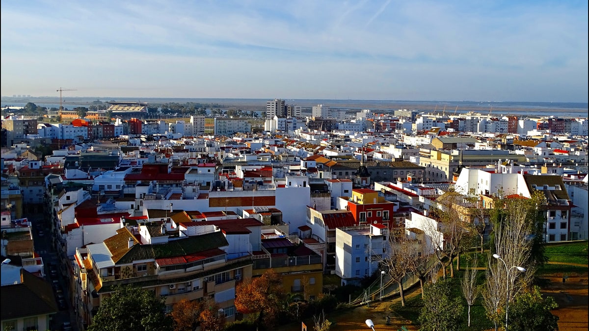 Vista aérea del casco urbano de Huelva con tejados rojos, edificios blancos y la línea del horizonte