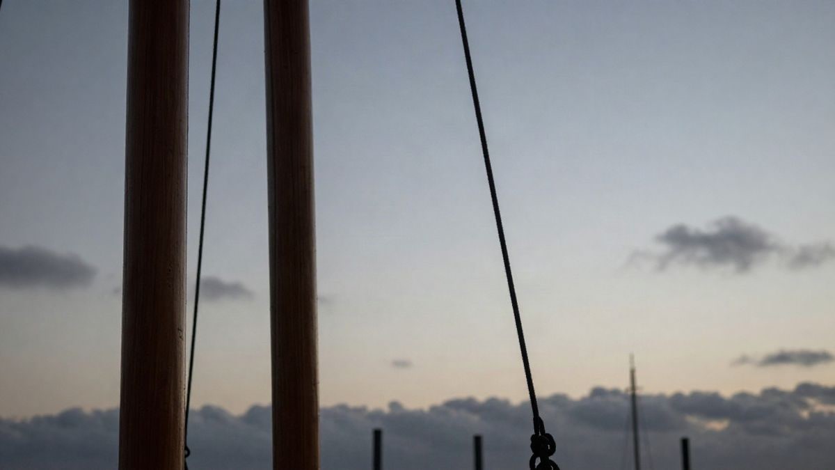 Imagen ilustrativa: mástil y jarcia de madera recortados contra un cielo al atardecer desde un ángulo bajo