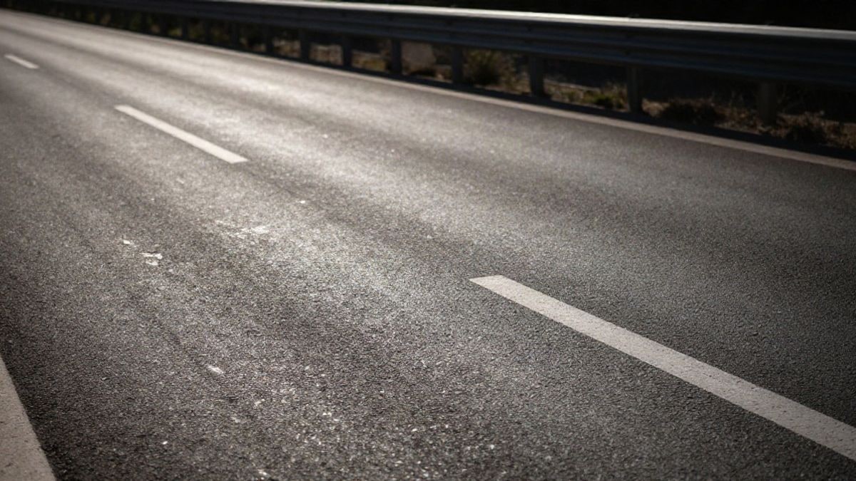 Imagen ilustrativa: detalle de textura de asfalto desgastado en una carretera con marcas viales desvaídas