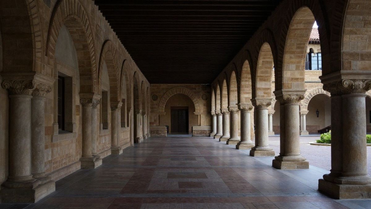 Imagen ilustrativa: gran angular de un patio universitario con arcos y columnas bajo luz natural