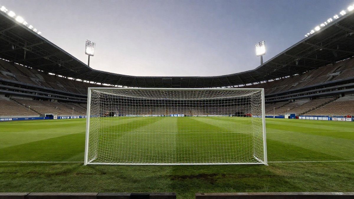 Imagen ilustrativa: gran angular de un campo de fútbol vacío al atardecer con las gradas y la portería al fondo