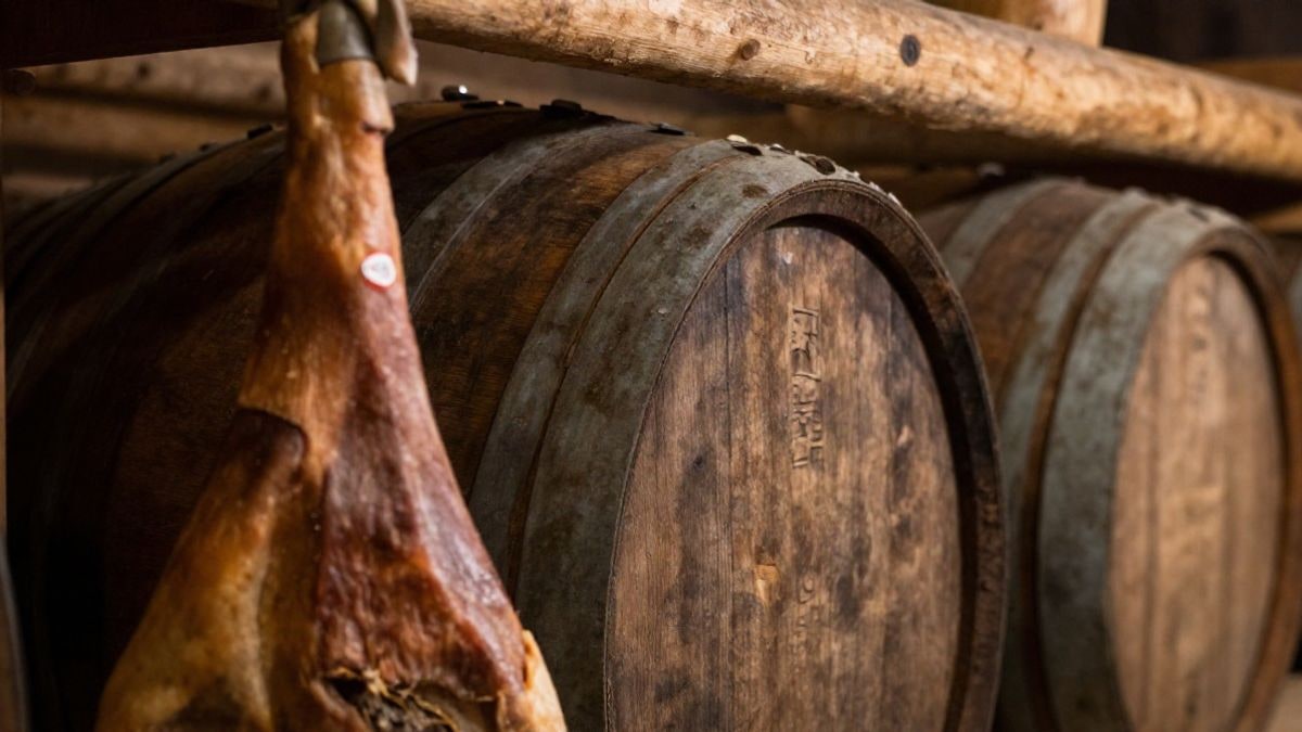 Imagen ilustrativa: detalle de madera envejecida y un jamón curado colgado en una bodega rústica