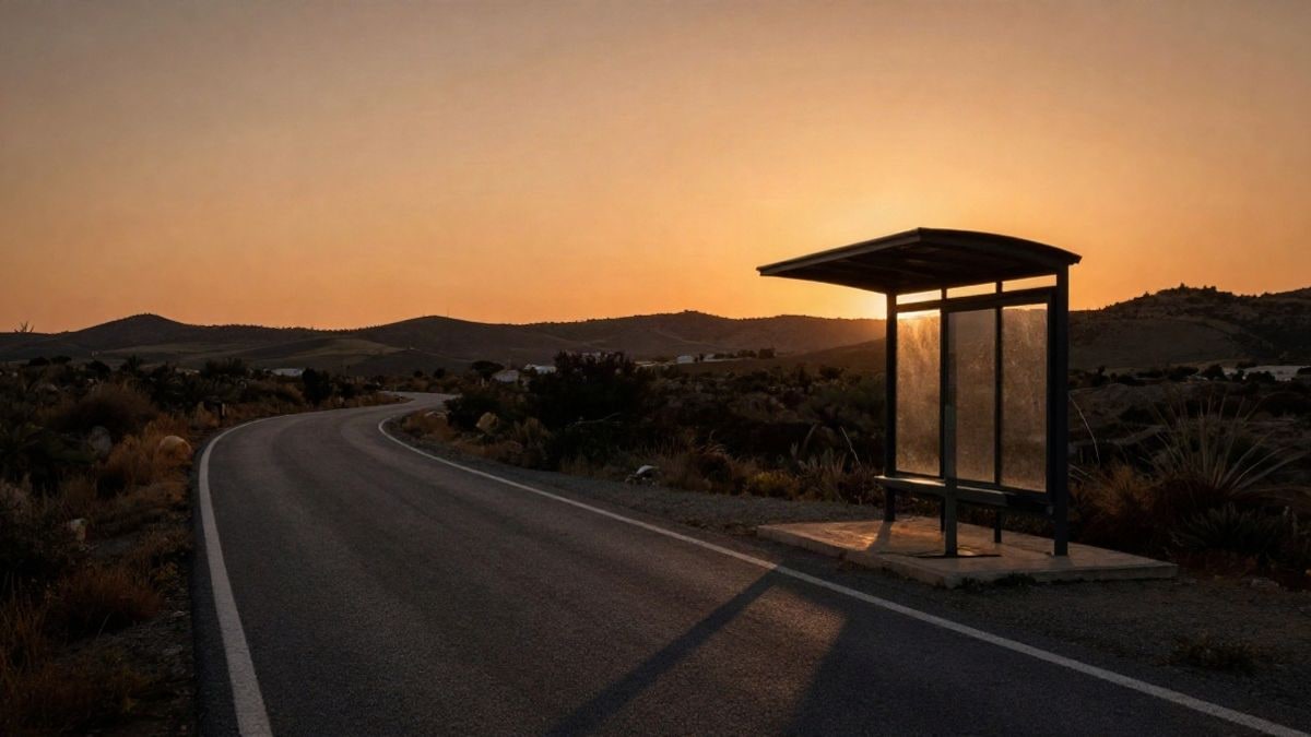 Imagen ilustrativa: una carretera rural al atardecer con una parada de autobús solitaria y sombras alargadas.
