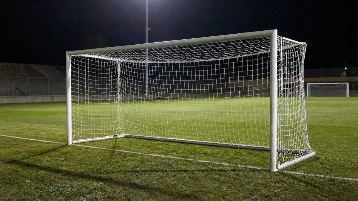 Imagen ilustrativa: portería de fútbol con la red a contraluz en un estadio vacío de noche