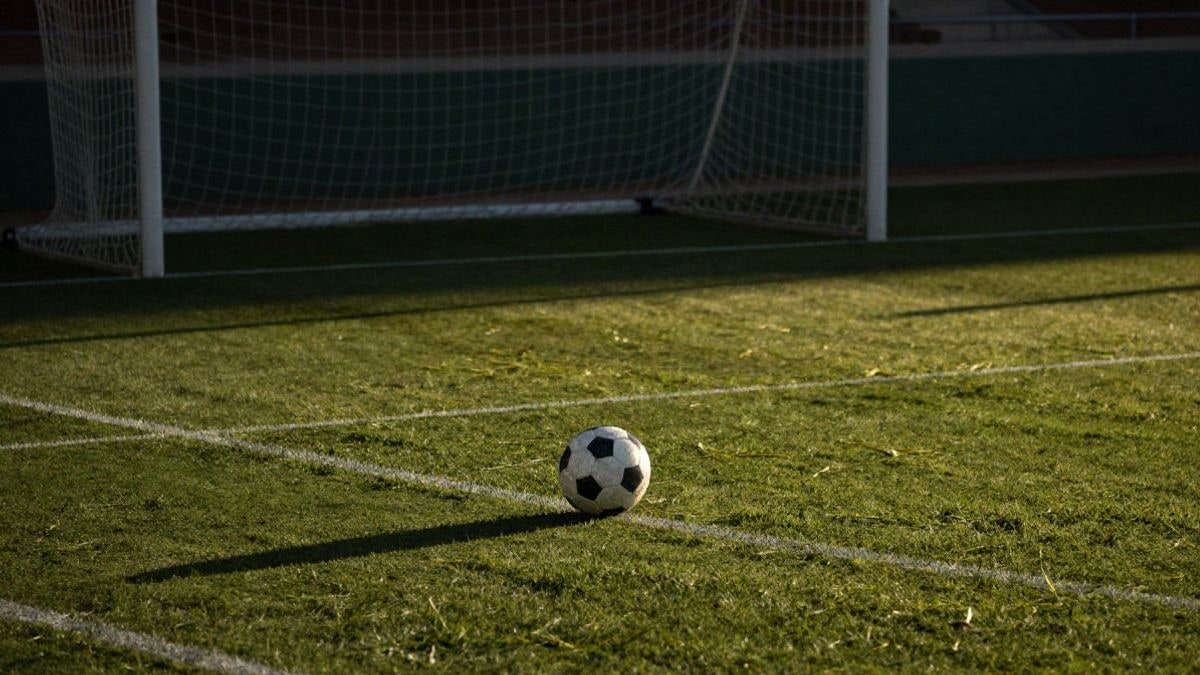 Imagen ilustrativa: balón de fútbol sobre el punto de penalti de un campo visto desde arriba al amanecer.