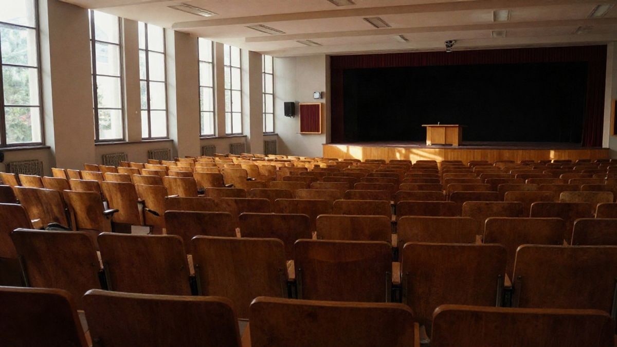 Imagen ilustrativa: un auditorio universitario vacío con filas de butacas y un atril en el escenario