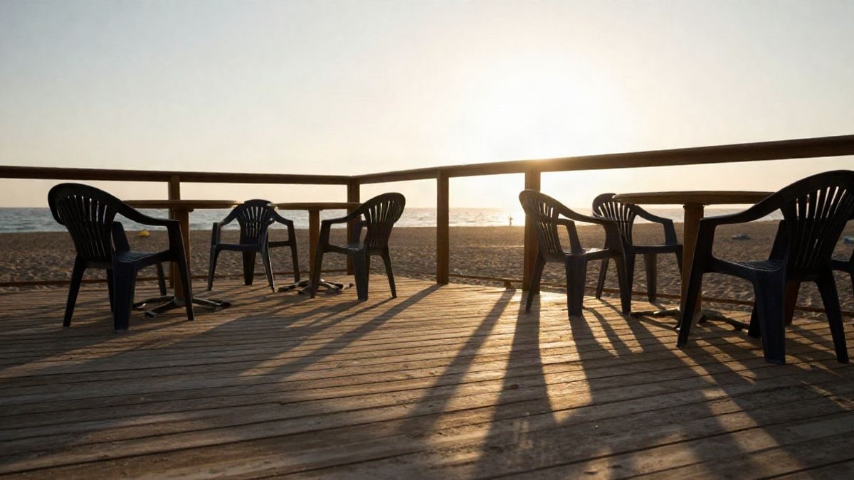 Imagen ilustrativa: terraza de madera de un chiringuito al atardecer, con sombras largas sobre la arena