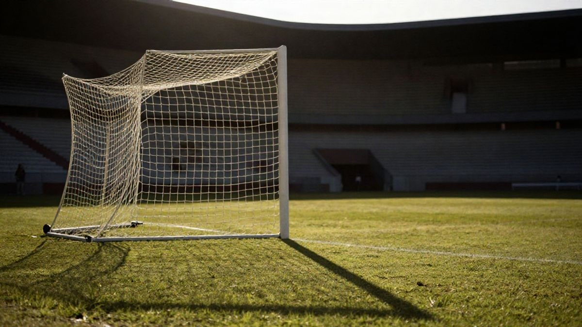 Imagen ilustrativa: una portería de fútbol con la red iluminada a contraluz al atardecer, en un estadio vacío