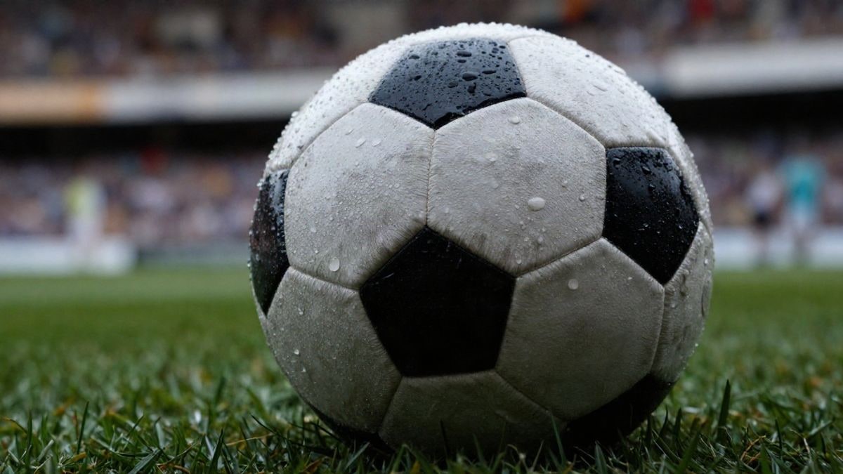 Imagen ilustrativa: primer plano macro de un balón de fútbol sobre el césped con gotas de agua