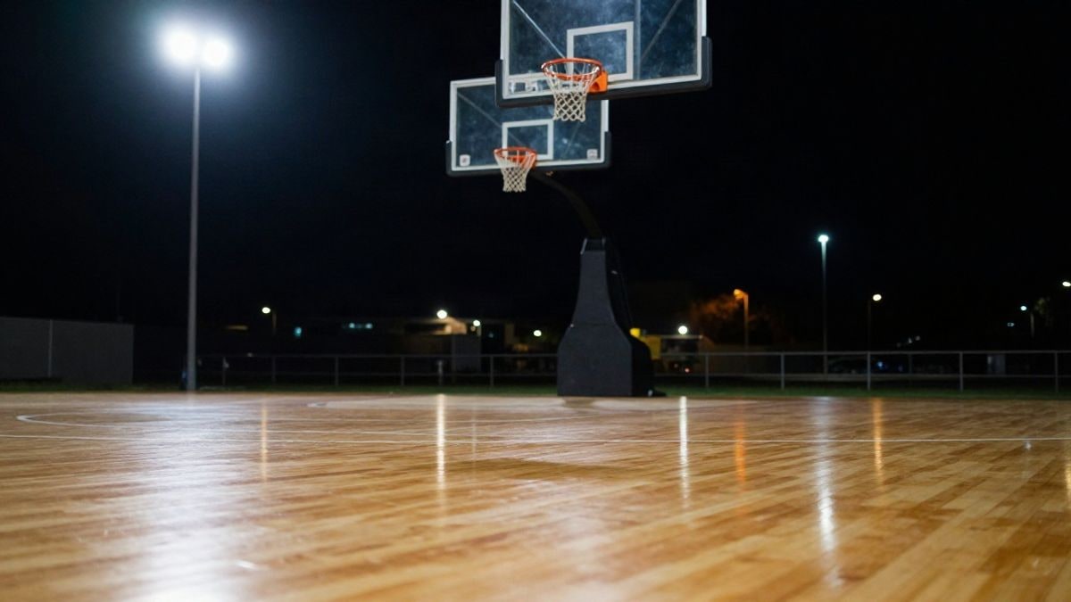 Imagen ilustrativa: canasta de baloncesto iluminada por focos de noche sobre una pista vacía