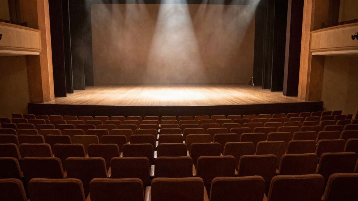 Imagen ilustrativa: patio de butacas de un teatro vacío con el escenario iluminado al fondo por un único foco