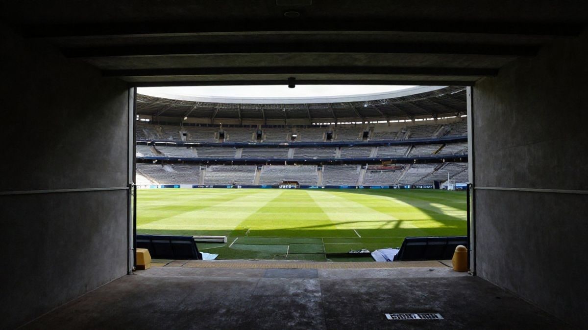 Imagen ilustrativa: túnel de vestuarios de un estadio de fútbol que conduce al césped, con luz natural y gradas vacías.