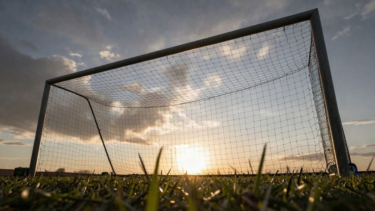 Imagen ilustrativa: portería de fútbol con red vista desde el suelo bajo un cielo al atardecer