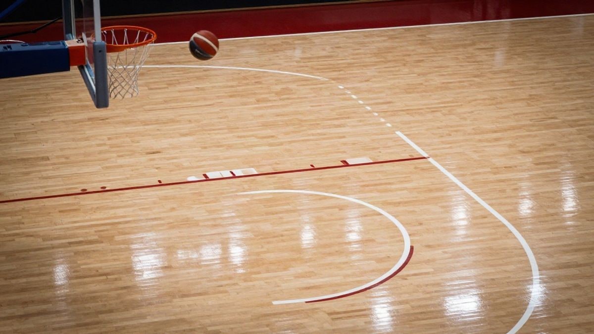Imagen ilustrativa: vista cenital de una cancha de baloncesto con un balón en la línea de tres puntos