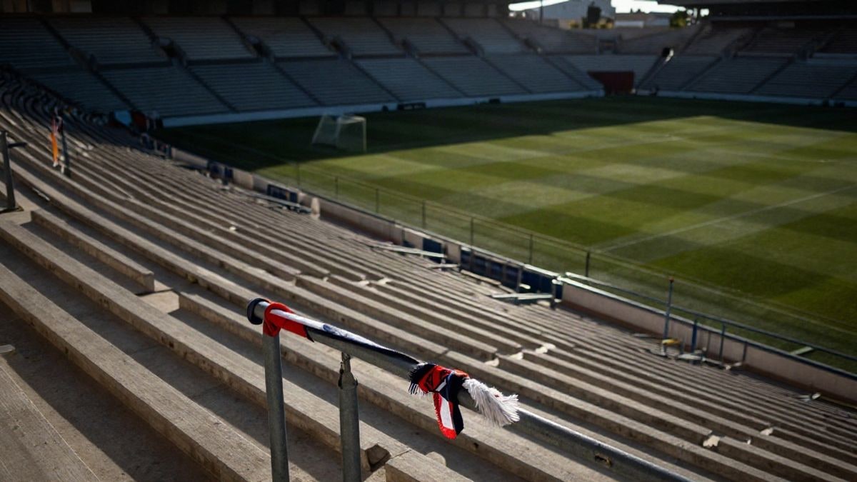 Imagen ilustrativa: grada vacía de un estadio modesto con una bufanda atada a la barandilla