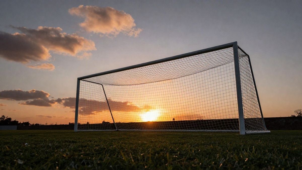 Imagen ilustrativa: ángulo bajo de una portería de fútbol con la red recortada contra el cielo al atardecer
