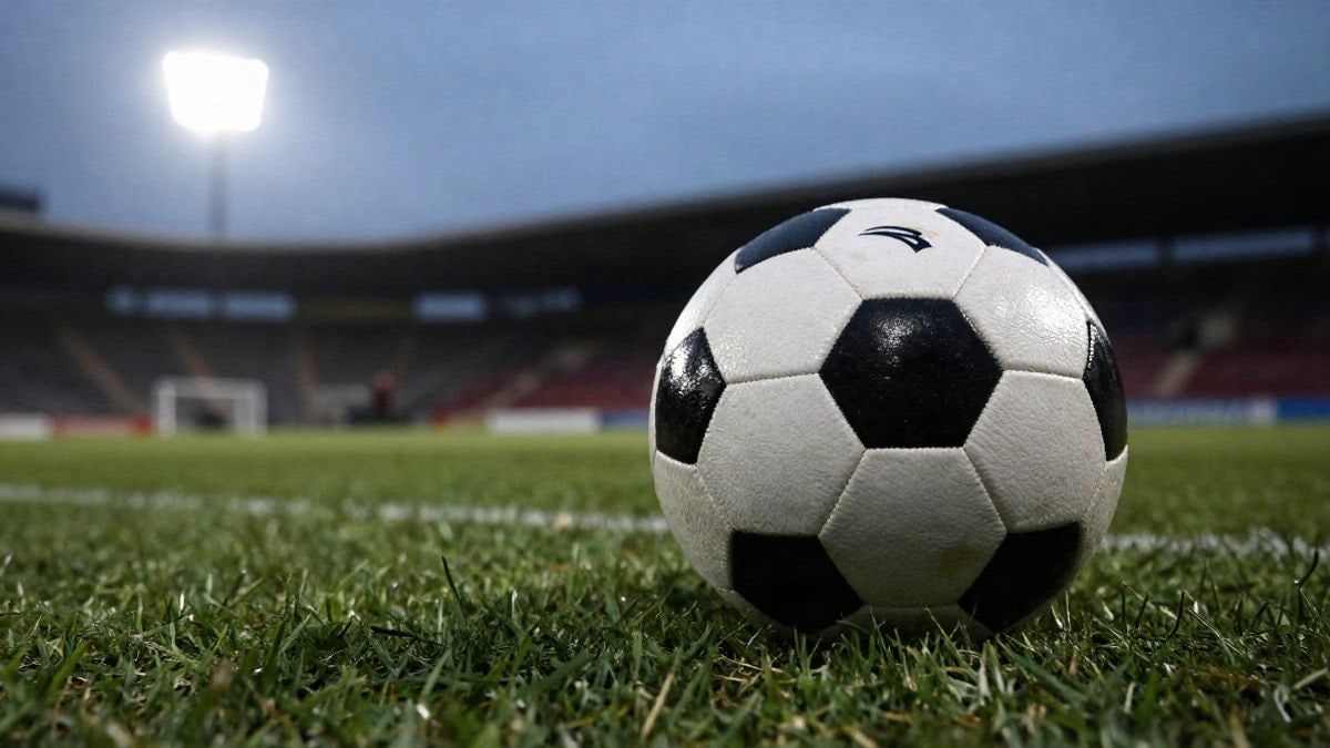 Imagen ilustrativa: un balón de fútbol sobre el césped al atardecer, con luces de estadio desenfocadas al fondo.