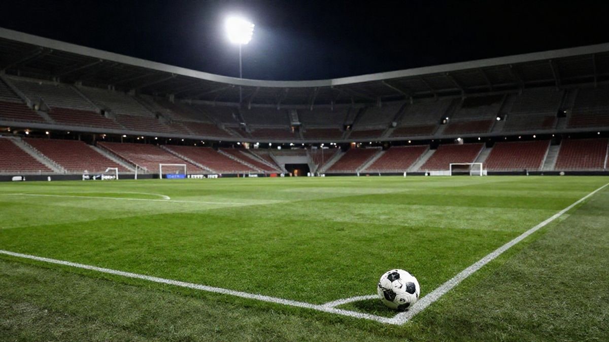 Imagen ilustrativa: un estadio de fútbol vacío iluminado por focos, con un balón en el punto de penalti