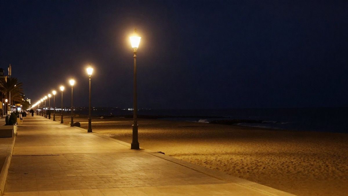 Imagen ilustrativa: paseo marítimo costero iluminado por farolas al anochecer junto al mar